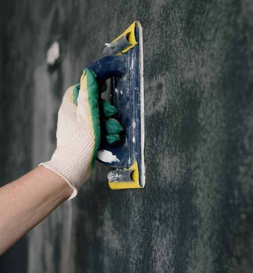Applying plaster to interior wall surface during plaster repair preparation