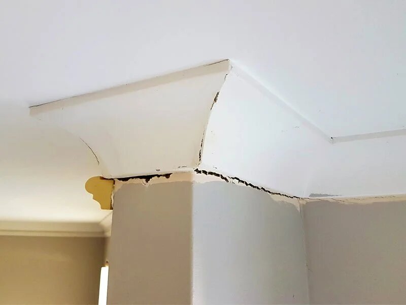 Cracked ceiling joint above interior wall showing movement and failed plaster repair