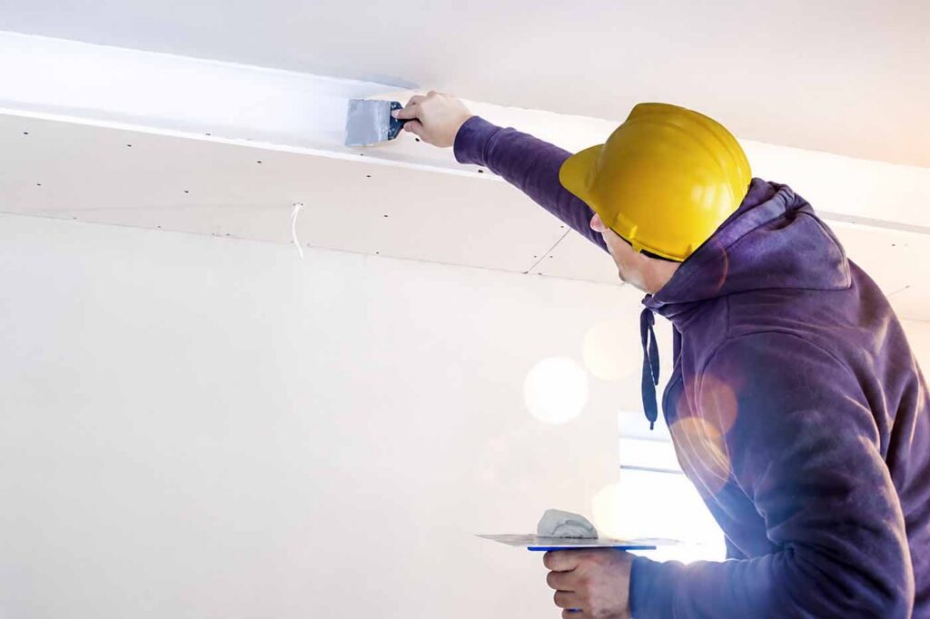Plasterer applying finishing compound to plasterboard joint for a smooth interior wall finish