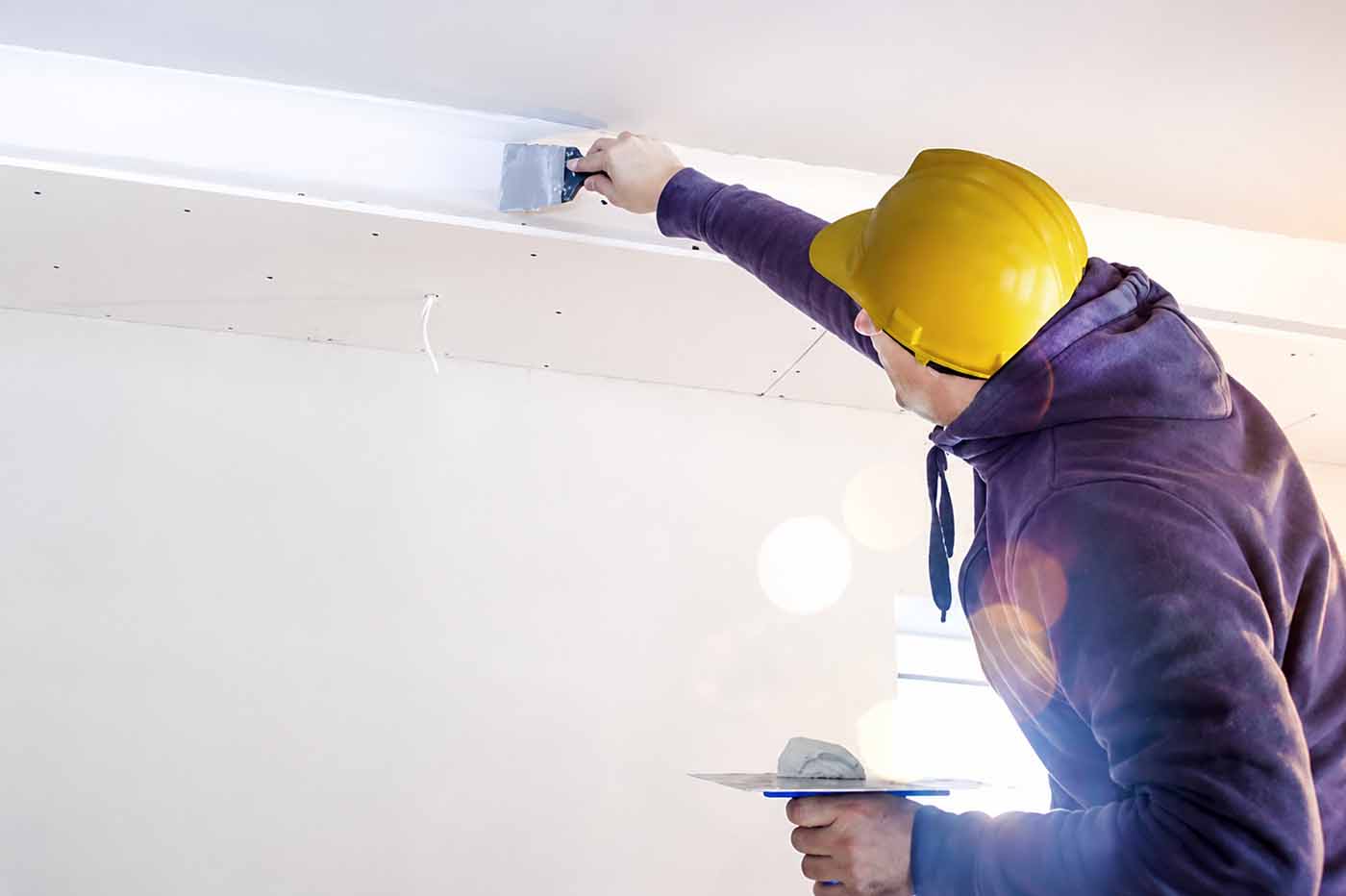 Plasterer applying finishing compound to plasterboard joint for a smooth interior wall finish