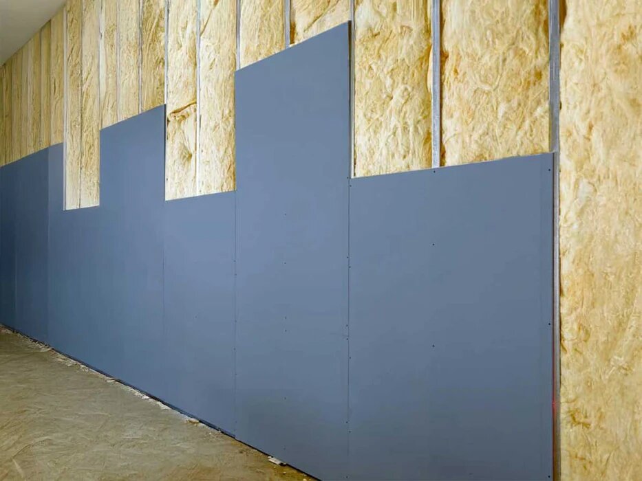 Acoustic plasterboard being installed over insulated internal wall for better sound control between rooms